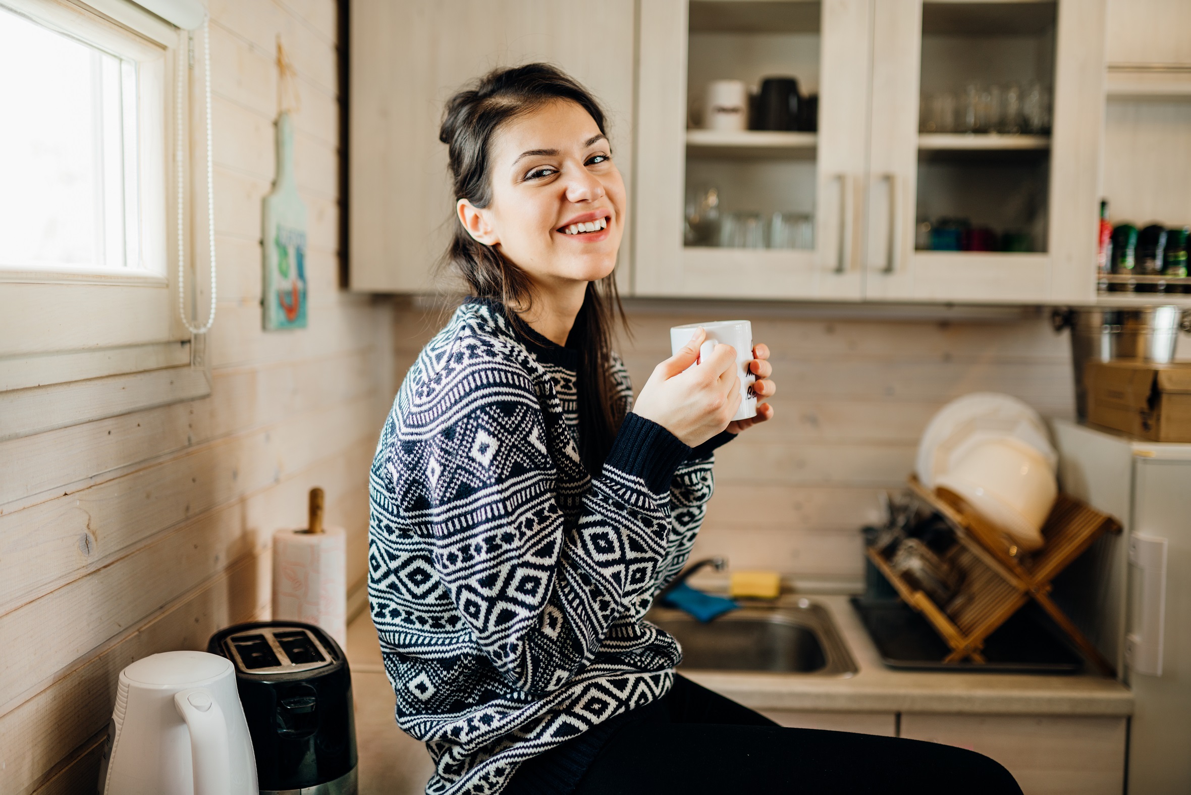  Eine Frau trinkt in ihrer Küche gemütlich Kaffee 