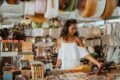 Auf dem Bild ist eine junge Frau zu sehen, die auf einem Markt Souvenirs betrachtet.