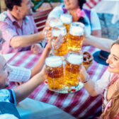 Eine Freundesgruppe in Trachten stößt mit Maßbier an.